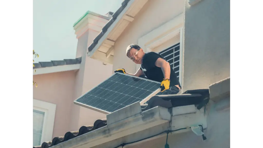 A technician in protective gear installs solar panels on a house roof, promoting sustainability and reflecting the growing housing trends pushing buyers toward smarter, energy‑efficient homes.