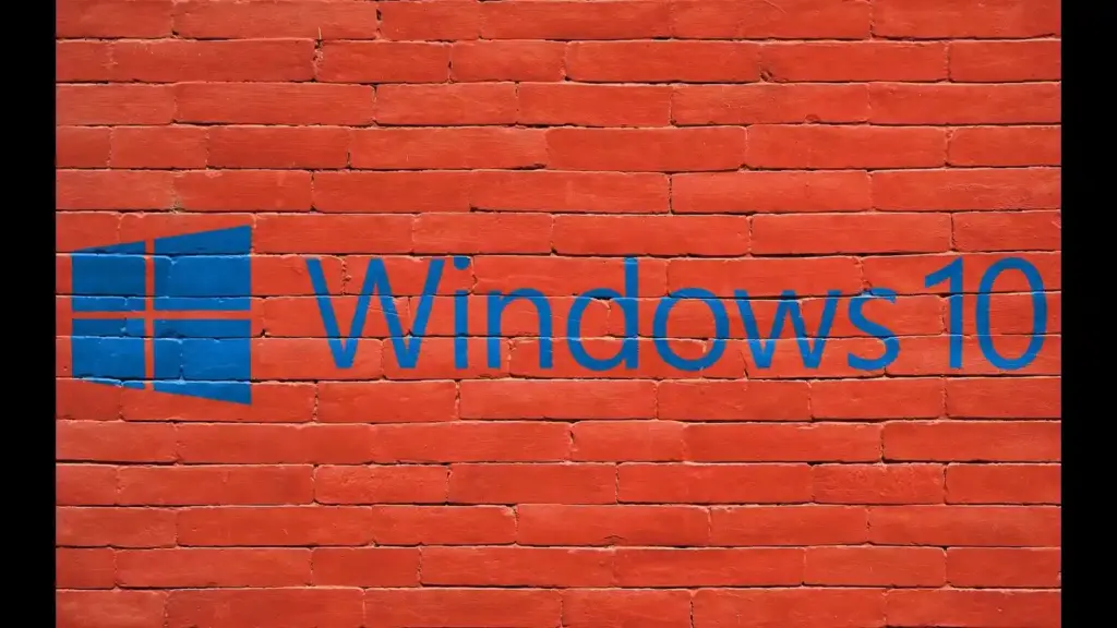 A blue Windows 10 logo and wordmark span a bright red brick wall, contrasting sleek technology branding with rough masonry in a bold, striking scene.