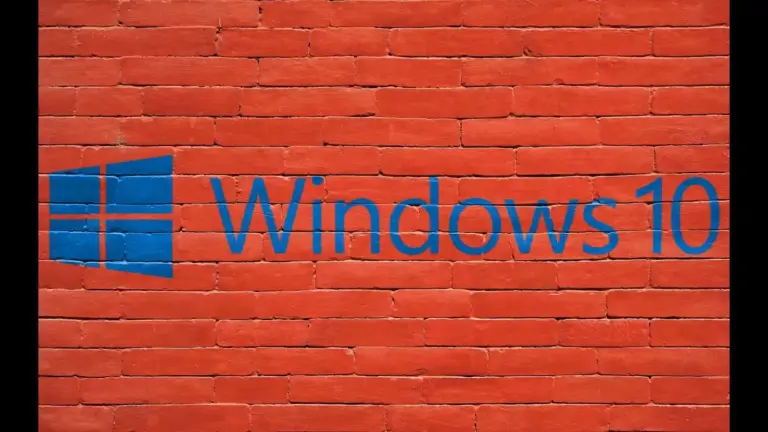 A blue Windows 10 logo and wordmark span a bright red brick wall, contrasting sleek technology branding with rough masonry in a bold, striking scene.