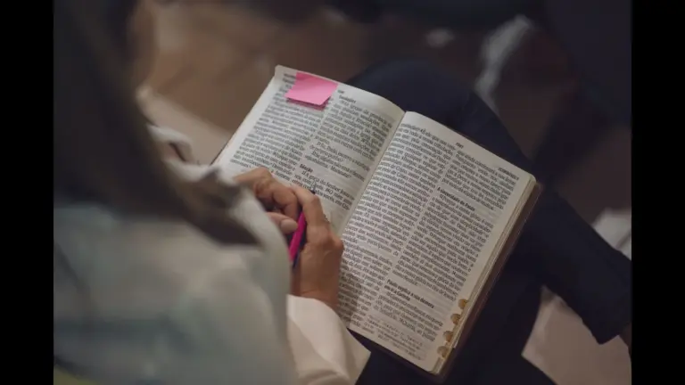 In Thursday's daily devotional, a woman studies the Bible, which has a sticky note on one side.