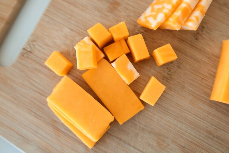 Cubes and slices of cheddar on a cutting board, the kind of cheese covered by the raw milk cheese recall