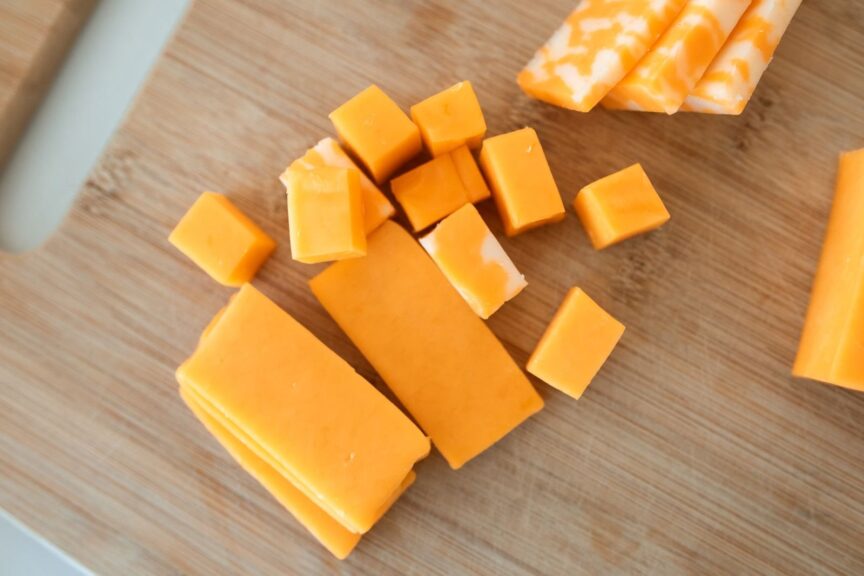 Cubes and slices of cheddar on a cutting board, the kind of cheese covered by the raw milk cheese recall
