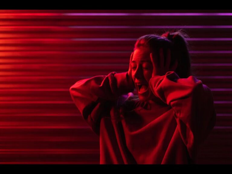 Woman holding her head under red light, illustrating a need for a quick stress reset