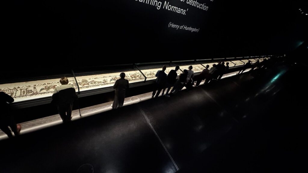 Visitors view the Bayeux Tapestry in a darkened British Museum gallery, the exhibition at the center of a Bayeux Tapestry lawsuit over audio description