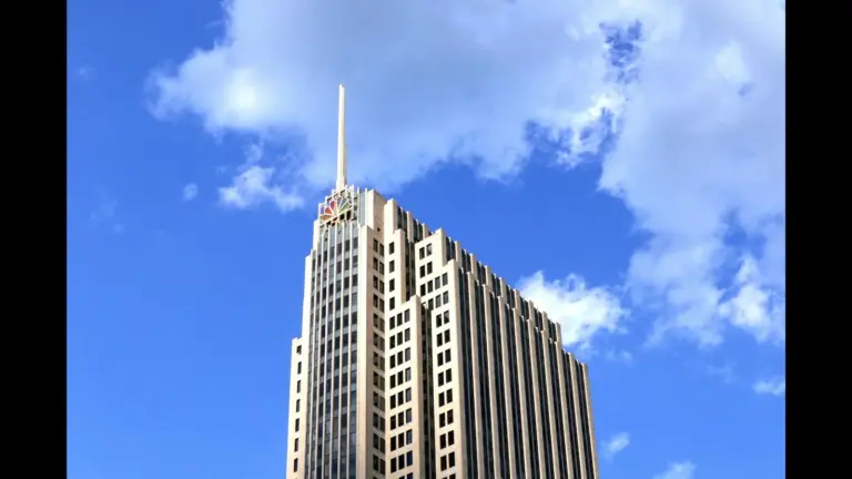 A tall building with a spire on top, against a blue sky with some clouds. NBC Universal, Action Arena