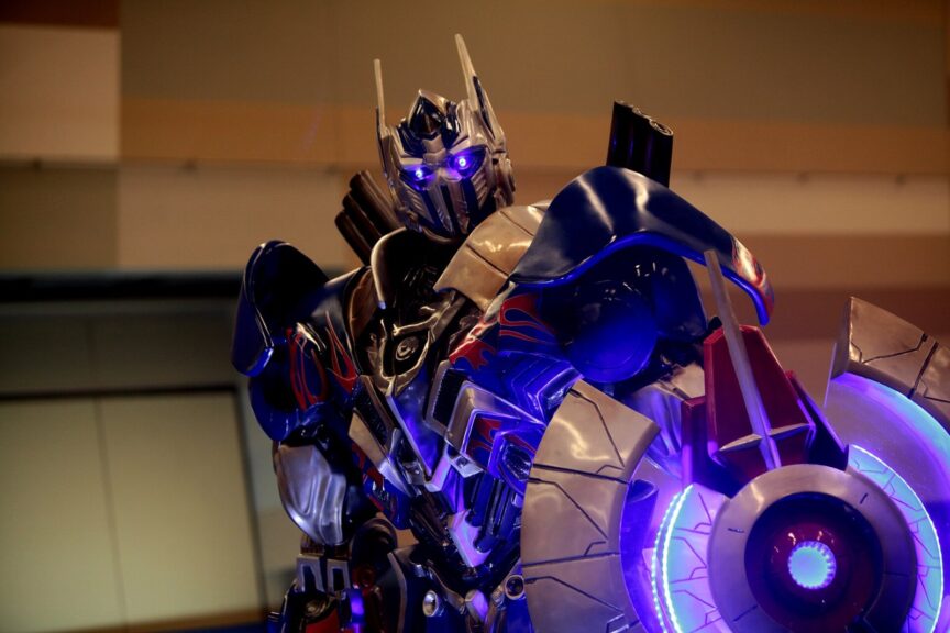 Optimus Prime statue representing the Transformers franchise behind the Kiss Players 20th anniversary set