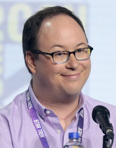 Lower Decks creator Mike McMahan smiles at a microphone during a Star Trek panel at San Diego Comic-Con in 2019