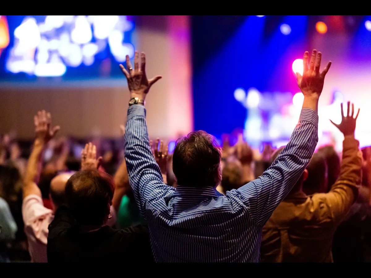 In Monday's daily devotional, a congregaton lifts their hands in praise to God in their sanctuary.